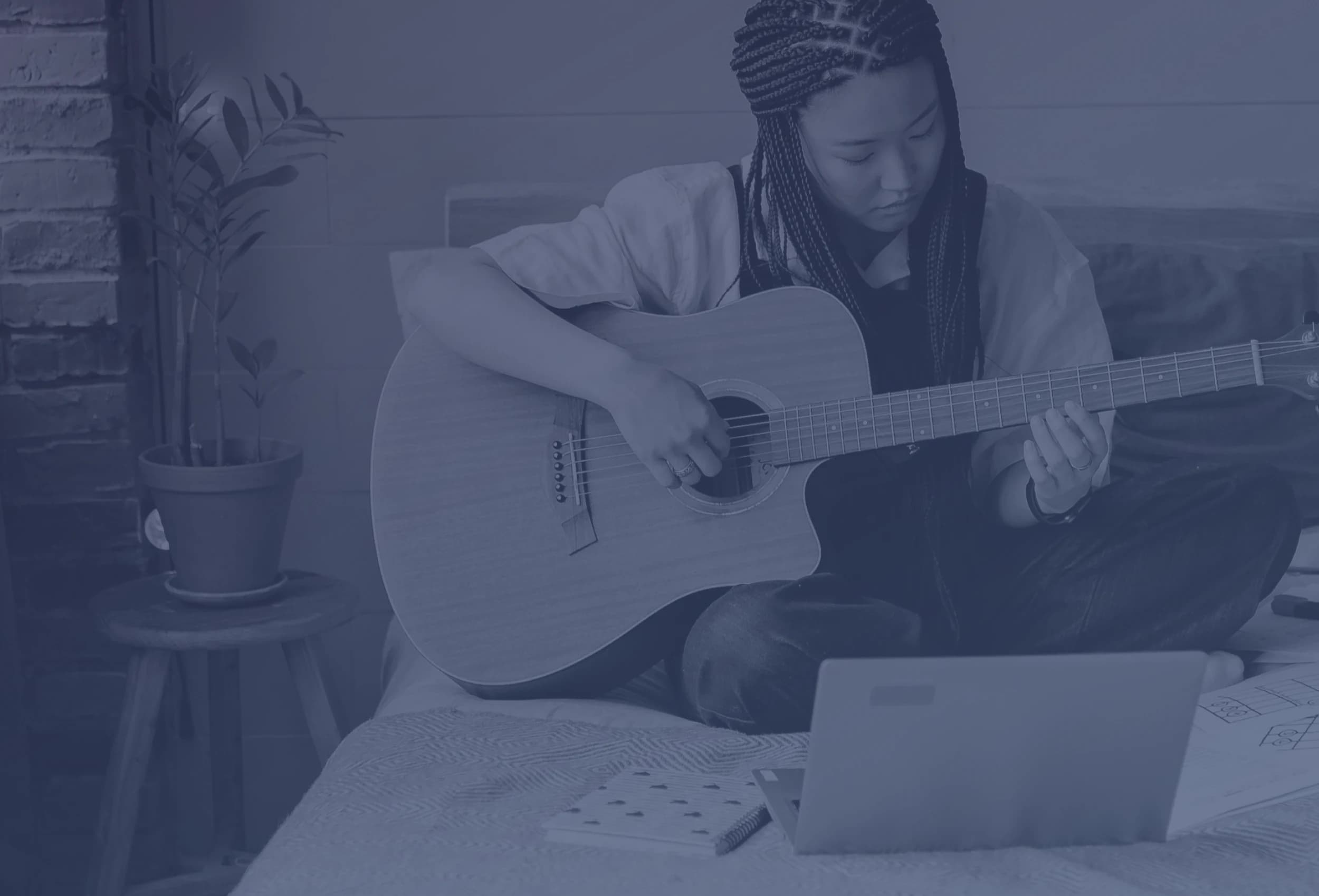 Student practicing guitar during an online lesson